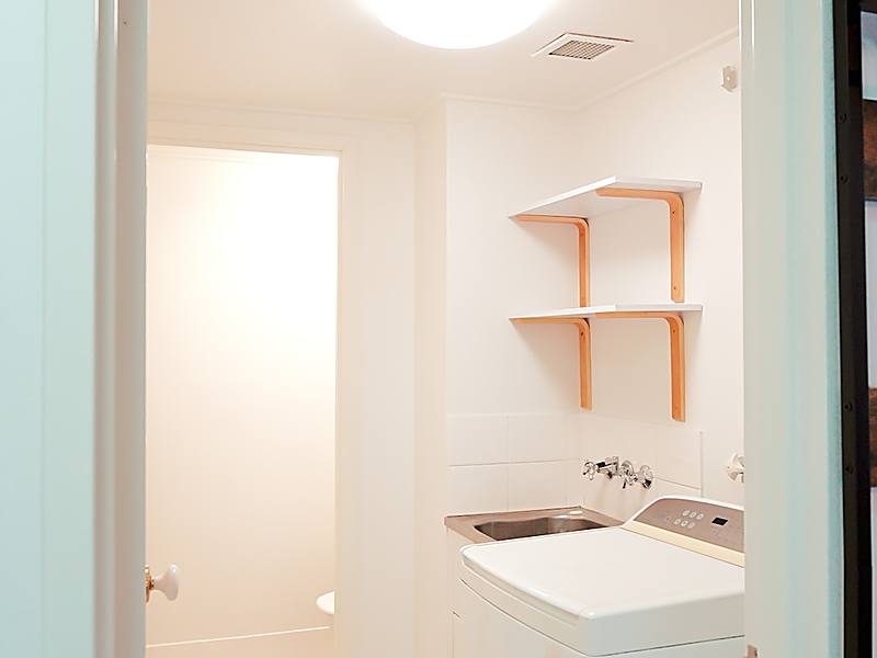 Original laundry with a washing machine, trough and separate toilet through a doorway