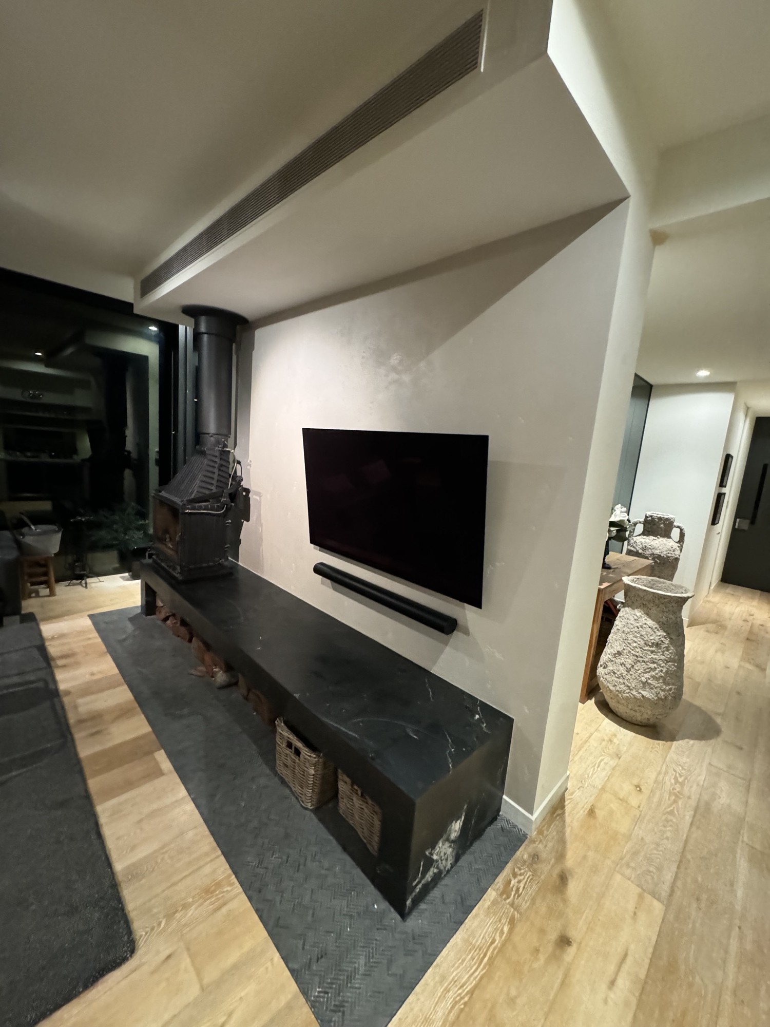 Architectural fireplace with black stone plinth and freestanding wood heater