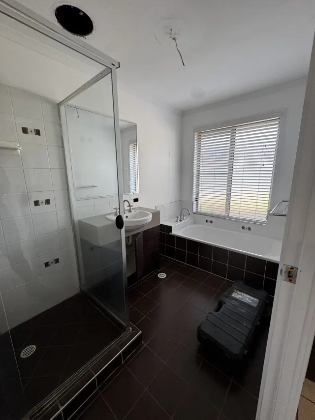 Before: the Regents Park bathroom with an inset bath, dark floor tiles and a framed shower