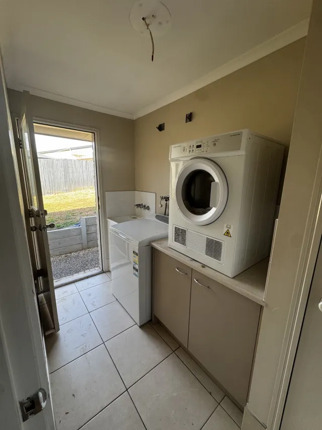 Original Regents Park laundry with a top-loading washing machine, dryer on a benchtop and low cupboards