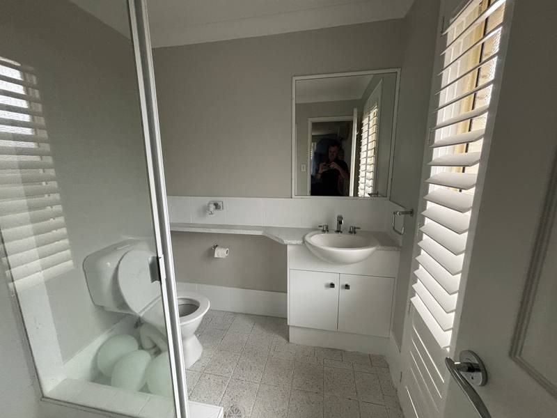 The original ensuite: single basin, framed shower, plain mirror