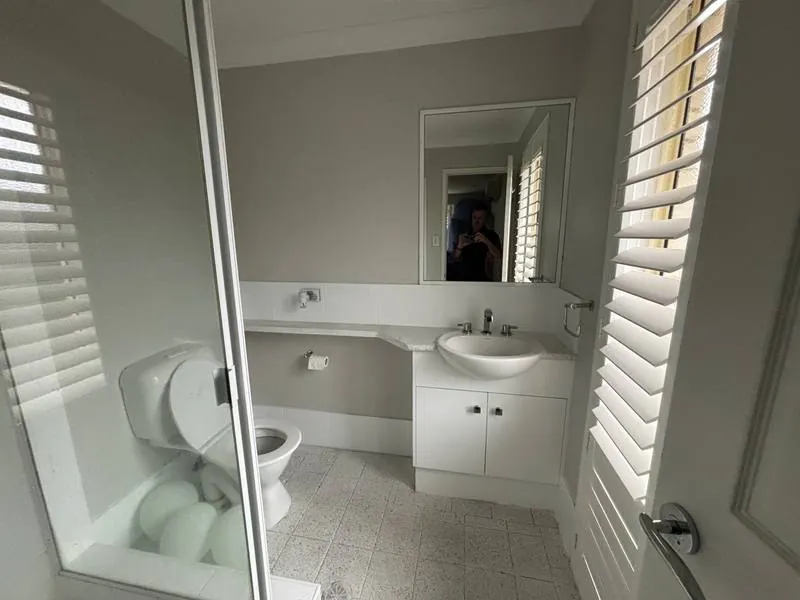 The original ensuite: single basin, framed shower, plain mirror