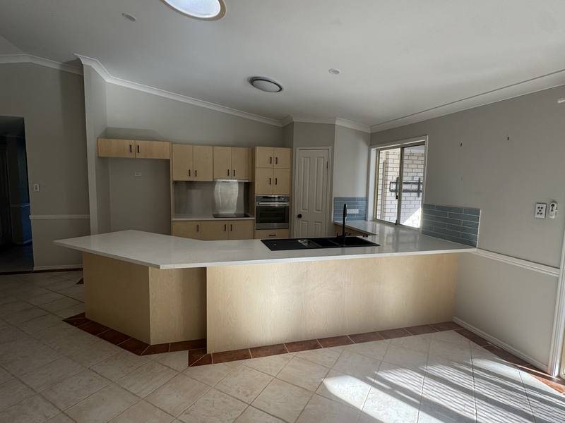The original kitchen: angled bench, timber-veneer cabinets, terracotta floor tile