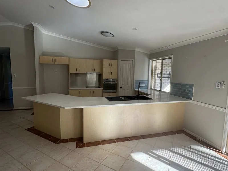 The original kitchen: angled bench, timber-veneer cabinets, terracotta floor tile