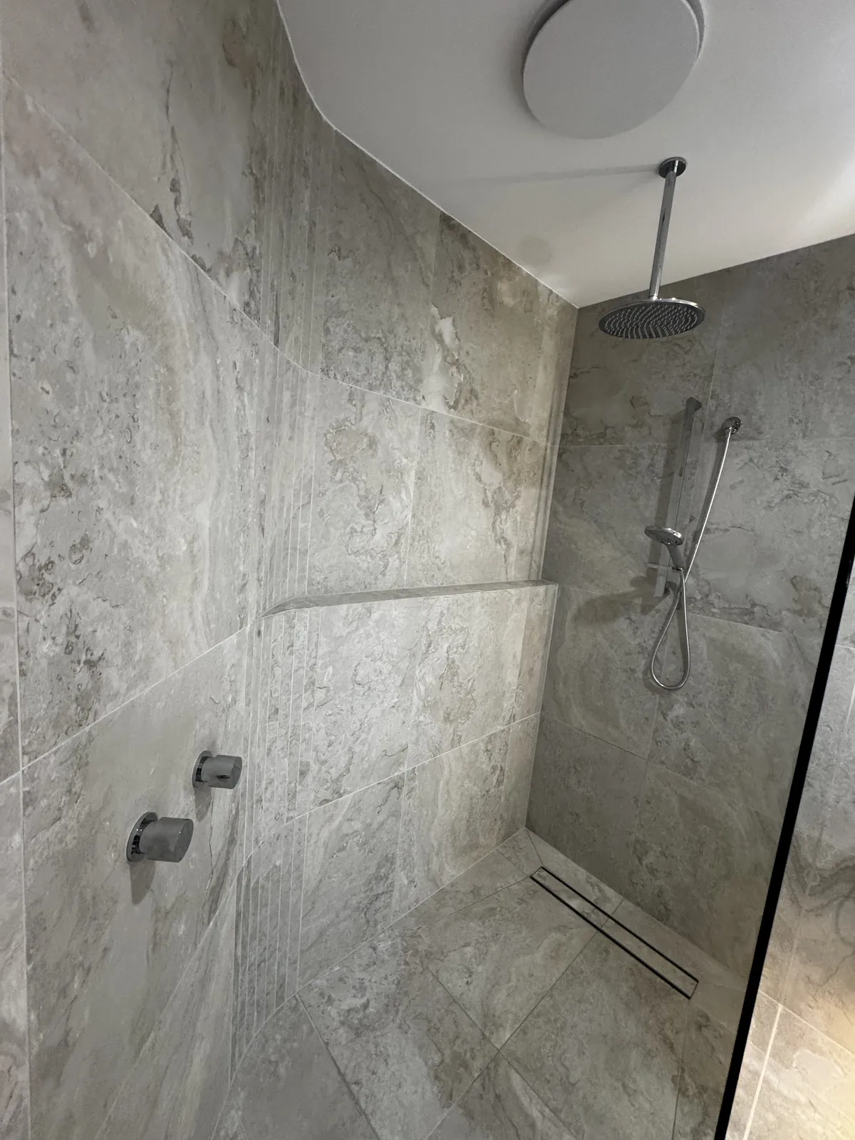 Walk-in shower with fixed glass panel