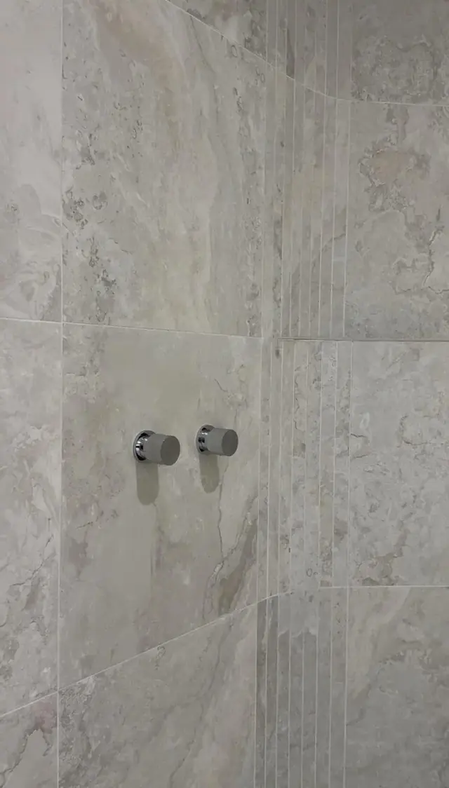 Travertine wall tile with fluted feature and wall mixers
