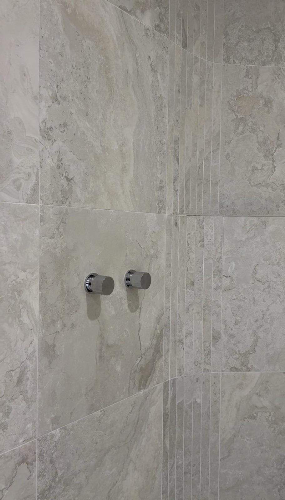 Travertine wall tile with fluted feature and wall mixers