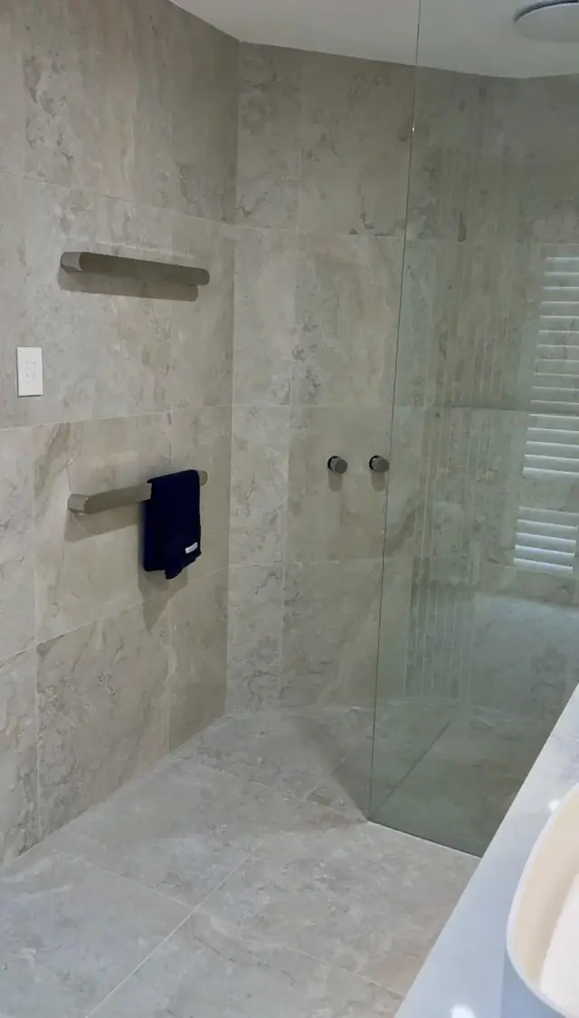 Heated towel rail beside a walk-in shower